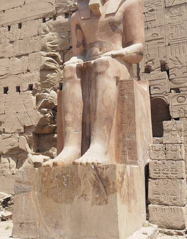 Close-up of ancient Egyptian statue feet with hieroglyphs.