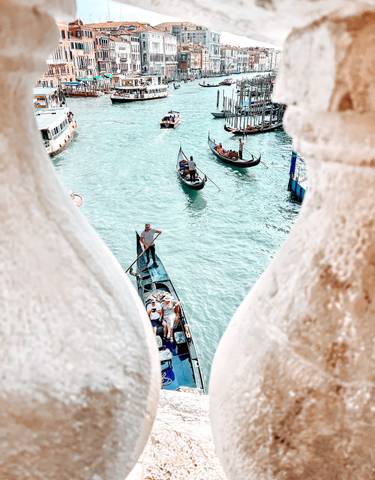 Gondolas on a Venetian canal viewed through a stone railing.