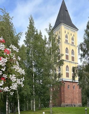 Tall, yellow church tower surrounded by trees.