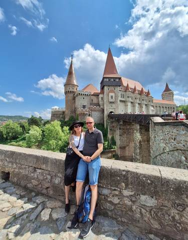 Couple posing in front of the large and historic Hunedoara Castle.