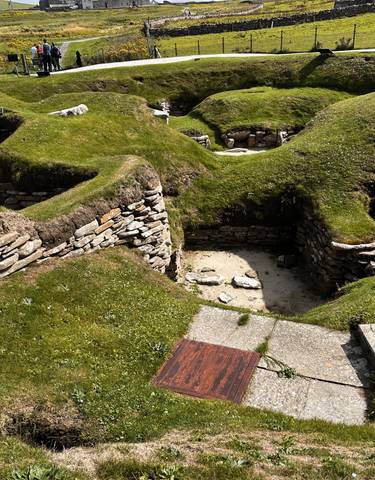Ruins of ancient stone structures on a grassy site.