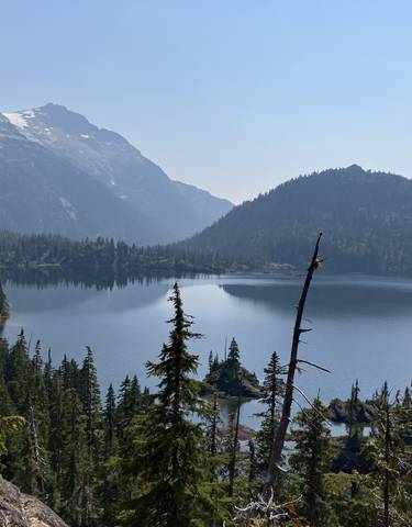 Serene mountain lake surrounded by forest and peaks.