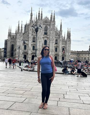 Woman posing in front of the Milan Cathedral in a busy plaza.