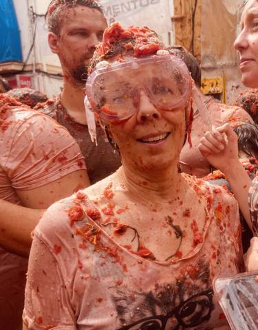 People participating in a tomato festival, covered in tomatoes.