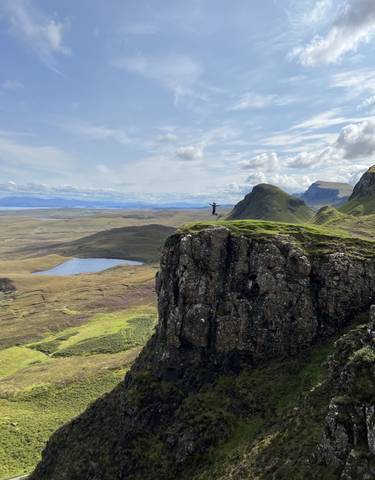 Person standing on a cliff with a panoramic view.
