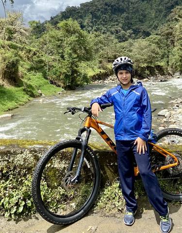 Person with a helmet and bicycle beside a scenic river.