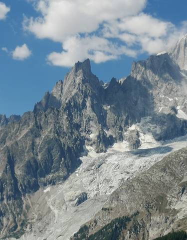 Mountain range with glaciers under a blue sky.