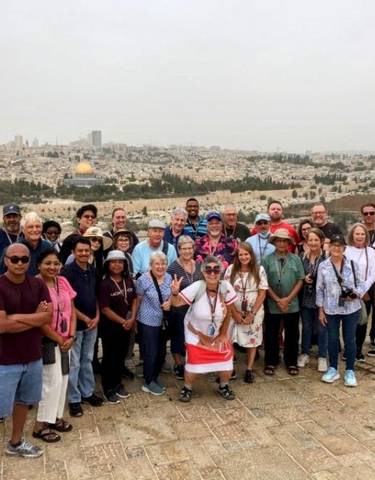 Group of tourists posing with a panoramic view of a cityscape.