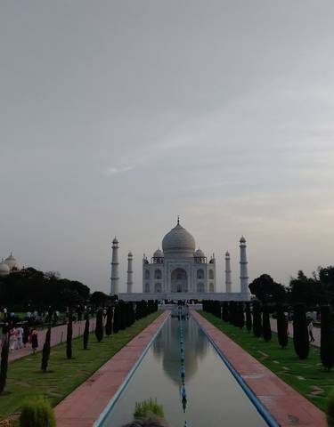 The Taj Mahal with visitors lining the gardens and reflecting pond.