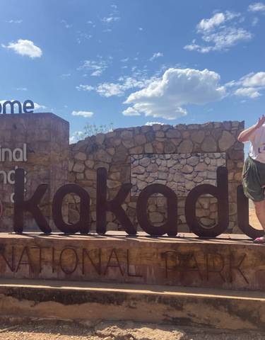 Person posing by the sign of Kakadu National Park.