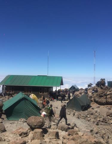 High-altitude camp with several tents and people.