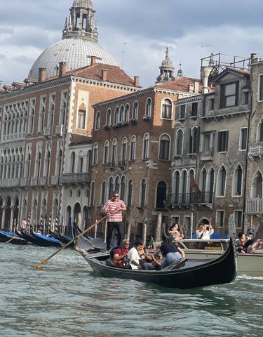 Venetian gondolas on a canal with historic buildings in the background.
