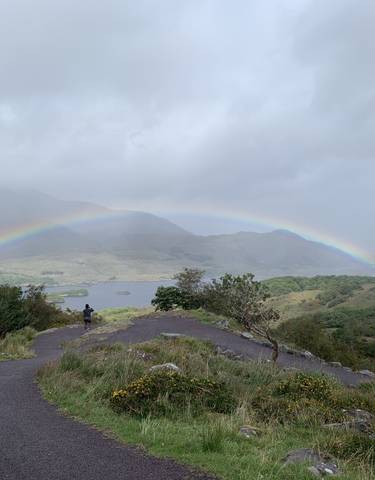 A scenic view of a rainbow over a hilly landscape.