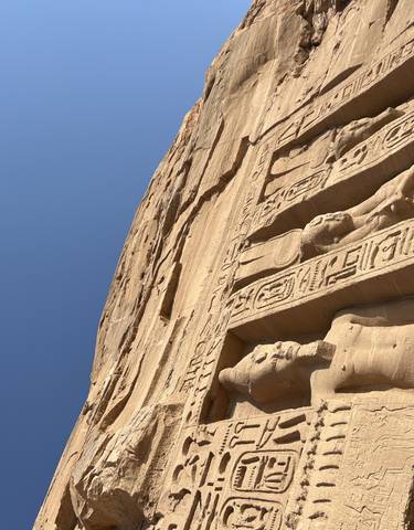 Close-up of hieroglyphics and carvings on an ancient stone wall.
