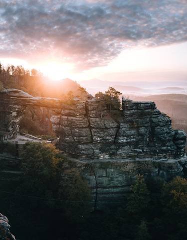 Dramatic sunrise over a rocky landscape with a house nestled on the cliffs.