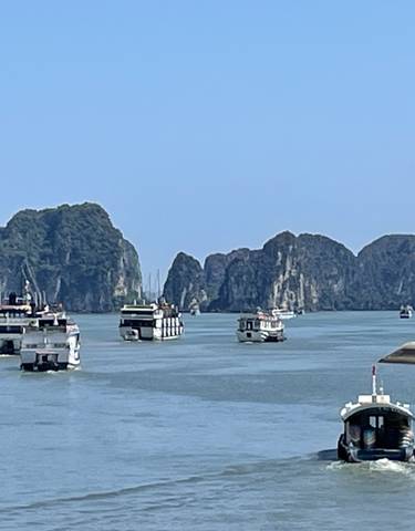 Boats sailing in a bay with limestone formations.