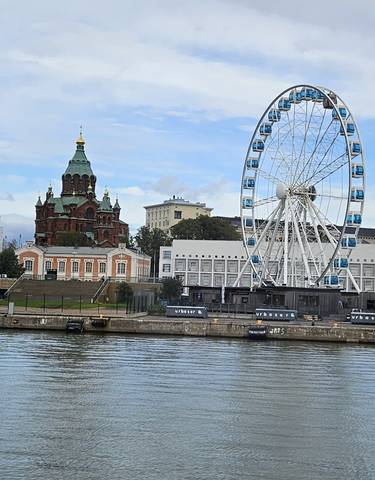 A cityscape featuring a cathedral and a Ferris wheel by a waterfront.