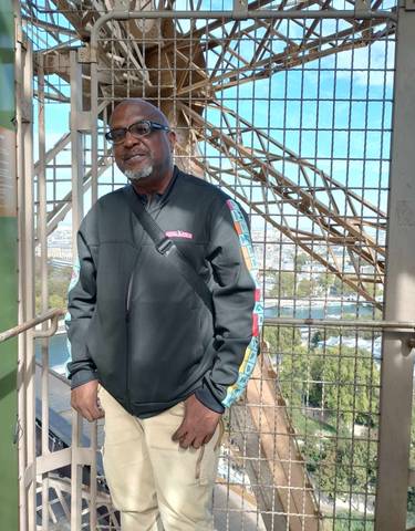 Person standing on the Eiffel Tower with city view.