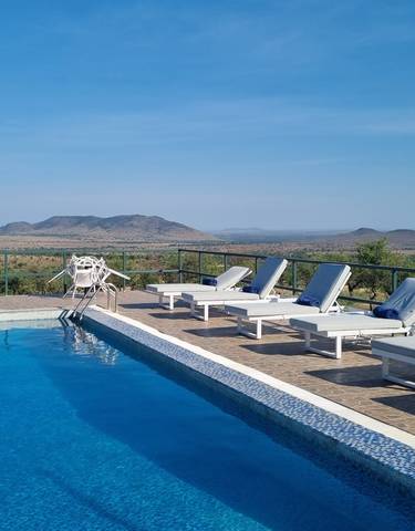 Swimming pool with loungers overlooking a scenic landscape.
