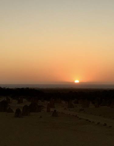 Sunset over a desert landscape with scattered formations.