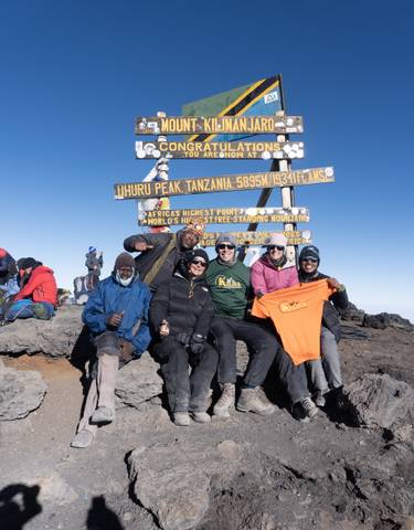 People celebrating with a sign at the summit of Uhuru Peak, Tanzania.