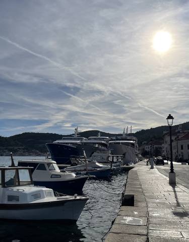 Several boats docked at a pier under a bright sunlit sky.