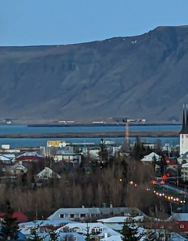 Panoramic view of a city with mountains and a large moon.
