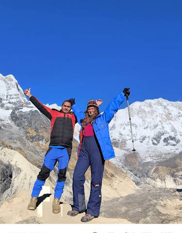 Two people posing with snowy mountains in the background
