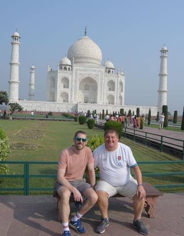 Two tourists posing in front of the Taj Mahal.