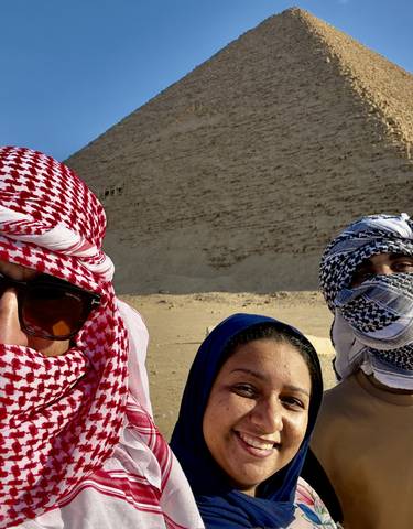 Three people posing in front of a pyramid.