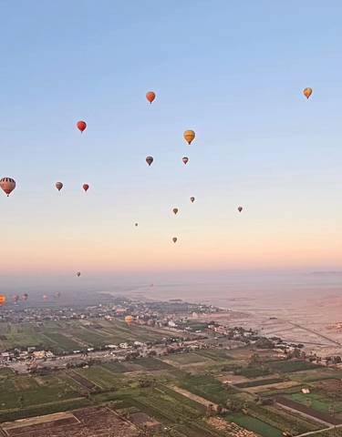 Hot air balloons floating over the desert landscape.