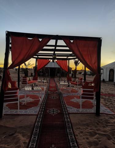 Outdoor seating area with red drapery at sunset.