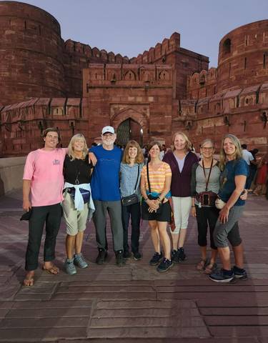 Group of people in front of a red sandstone fort's gate.
