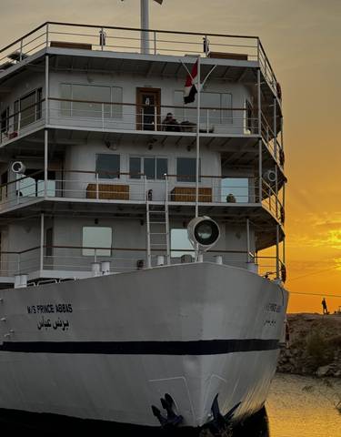 A large cruise ship at sunset on a river.