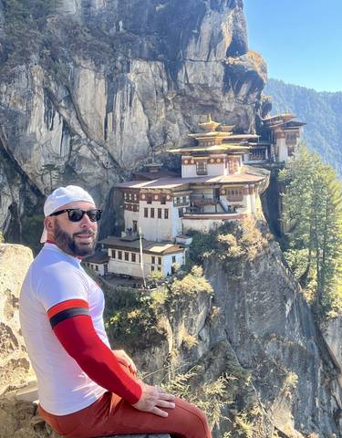 A man standing in front of the Paro Taktsang Monastery.
