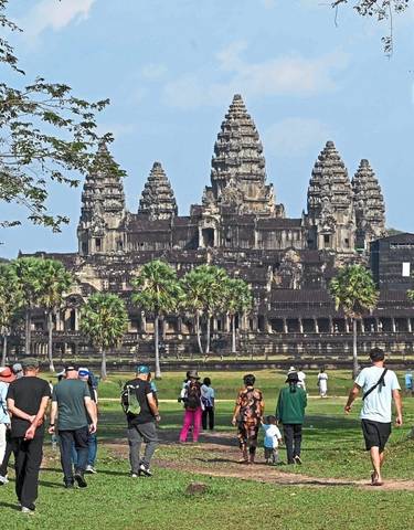 Group of people walking towards the Angkor Wat temple.