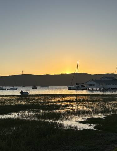 Sunset over a harbor with boats and calm waters.