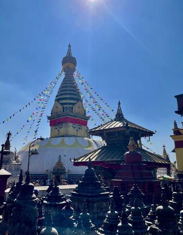 Boudhanath Stupa with prayer flags and clear blue sky.