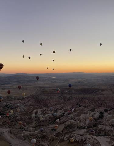 Hot air balloons floating over Cappadocia at sunrise.