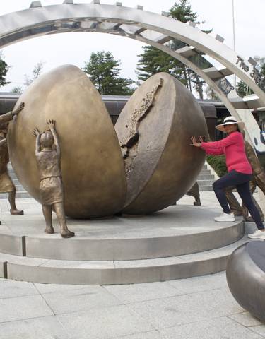 Tourist posing with sculptures of a divided sphere.