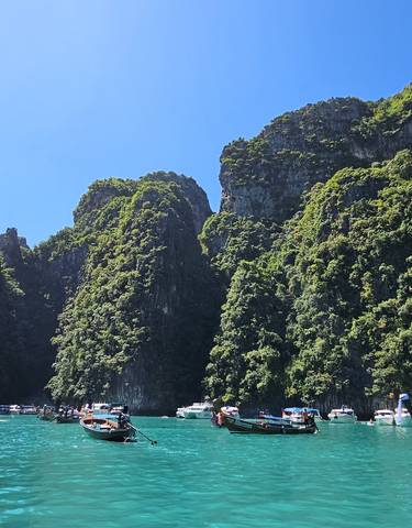 Boats and tourists in turquoise waters surrounded by limestone cliffs.