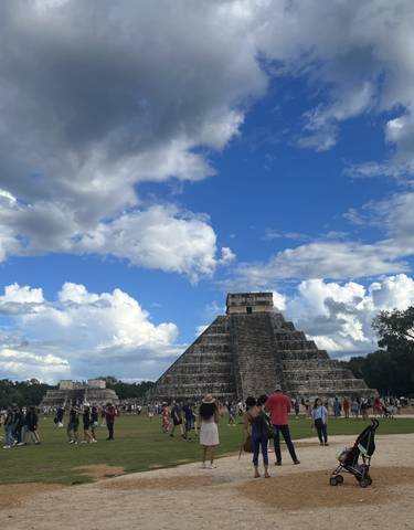 Chichen Itza with tourists on a sunny day.
