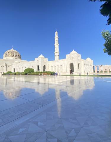 Beautiful mosque with a tall minaret reflected on polished ground.