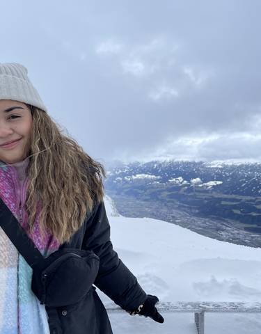 Woman smiling in a snowy mountain landscape.