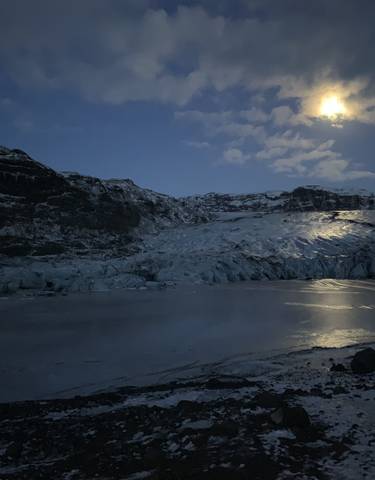 Nighttime view of a glacier under a bright moon.