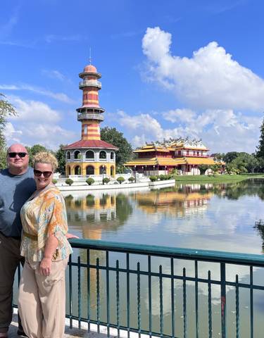 A couple posing in front of a scenic building and water reflection.