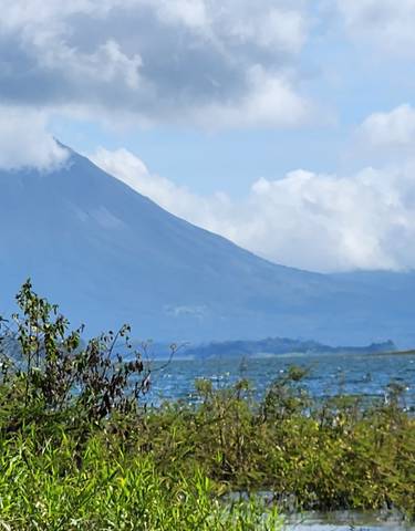Volcano in the distance with a lake and vegetation.