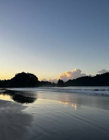 Calm beach at sunset with waves lapping against the shore.