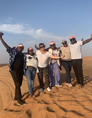 Group of people joyfully posing on a desert dune.