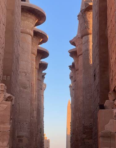 Tall ancient pillars with hieroglyphs under a clear blue sky.